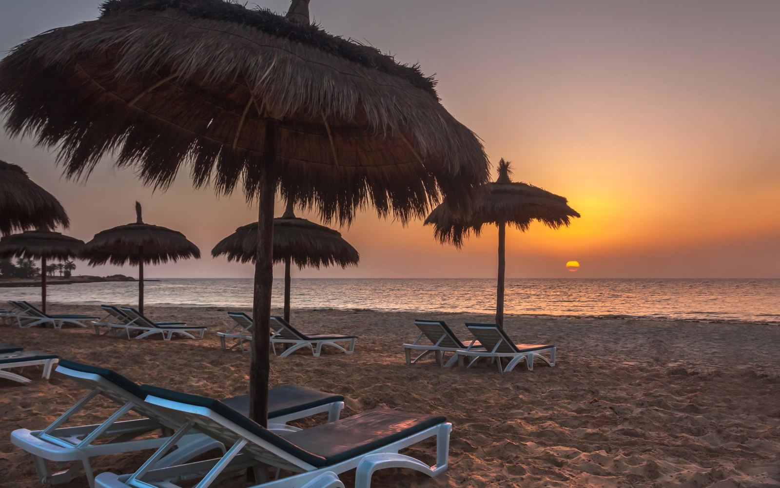 Sunset over the sandy beach with parasols at El Mouradi Djerba Menzel, Tunisia holiday - Sunshine4u